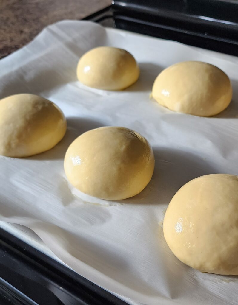 Buns on pan with parchment paper before baking.