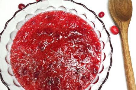 Fresh Cranberry Sauce in bowl with wooden spoon