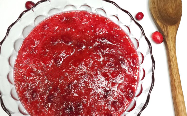 Fresh Cranberry Sauce in bowl with wooden spoon